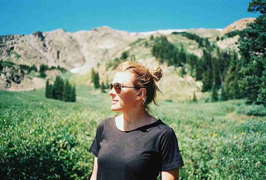 a person standing in a field of flowers with mountains in the background