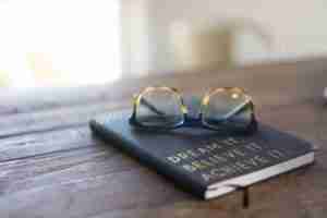 black and brown eyeglasses on book on brown wooden table