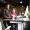 Two people working together at a desk witha computer and each are smiling