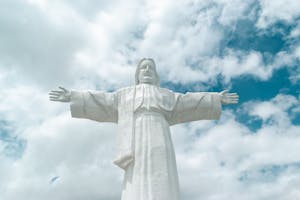 Majestic statue of Jesus Christ surrounded by a beautiful, cloudy sky.